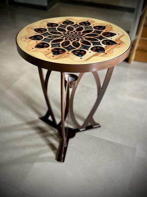Table bistrot rosace. Piètement en acier en forme d'ogive, plateau en bois massif, motif semi transparent en résine epoxy. Grace à la source de lumière intégrée, il se dégage une lumière d'ambiance.