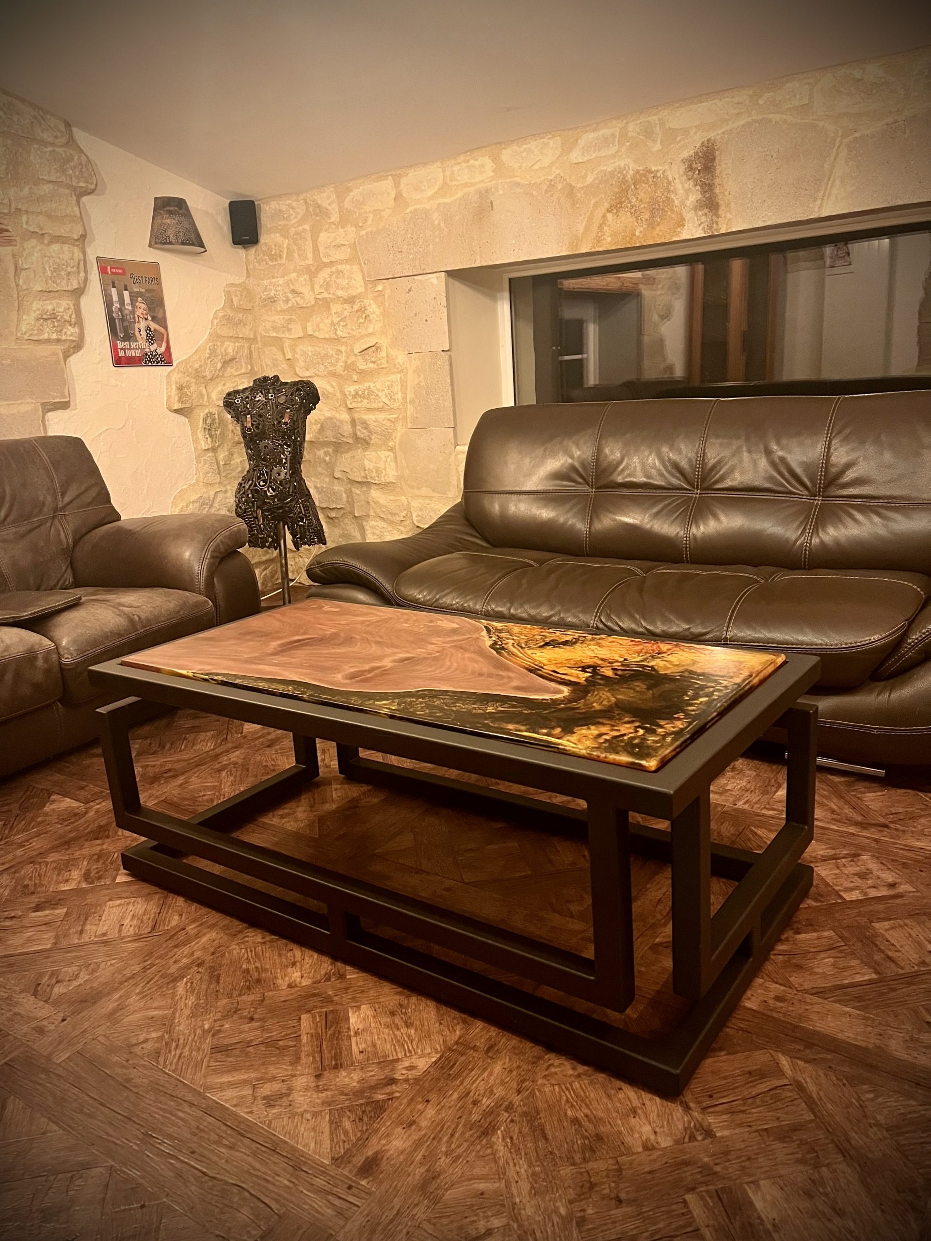 Table basse avec contour en métal. Pour le plateau, mélange de bois et de résine époxy.