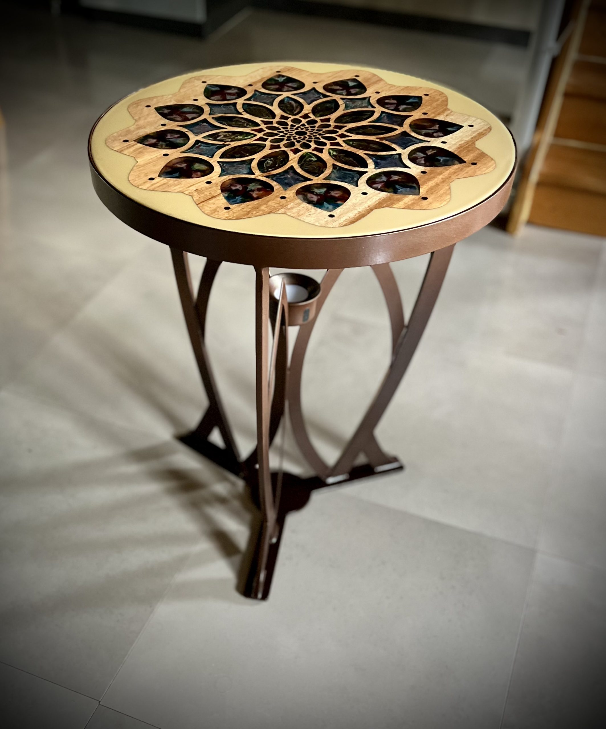 Table bistrot rosace. Piètement en acier en forme d'ogive, plateau en bois massif, motif semi transparent en résine epoxy. Grace à la source de lumière intégrée, il se dégage une lumière d'ambiance.